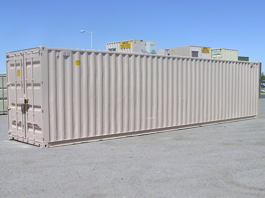 a 45 ft dirty white container with a yellow sticker in it saying maloy mobile storage with the company contact number, behind the container are more storage containers with different colors.
